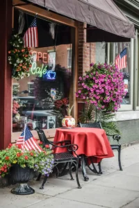 Small business storefront with American flags, flower displays, and outdoor seating for 4th of July