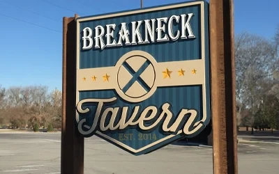 Exterior monument sign for Breakneck Tavern with raised lettering and decorative star elements on blue background